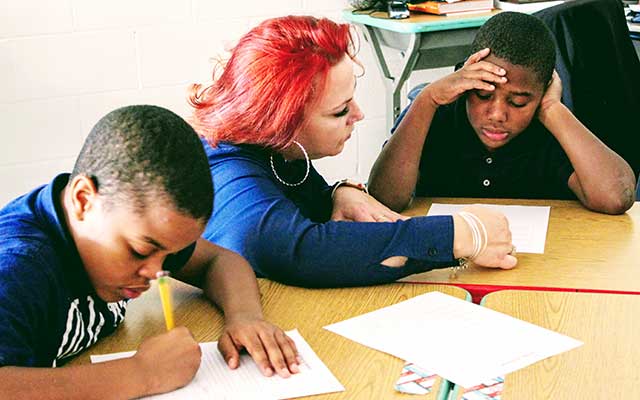 Teacher with red hair helping two African-American male students