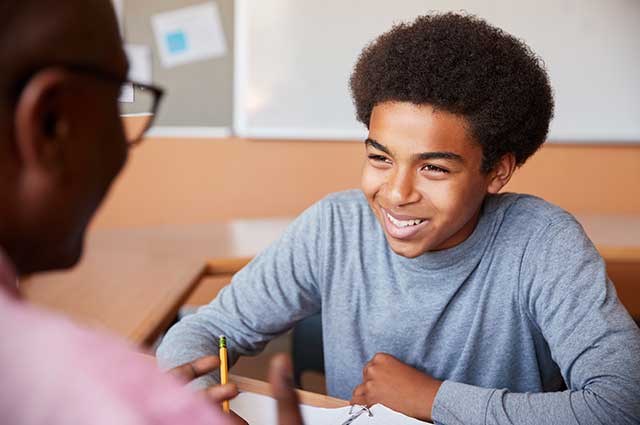 Young African-American male smiles with teacher