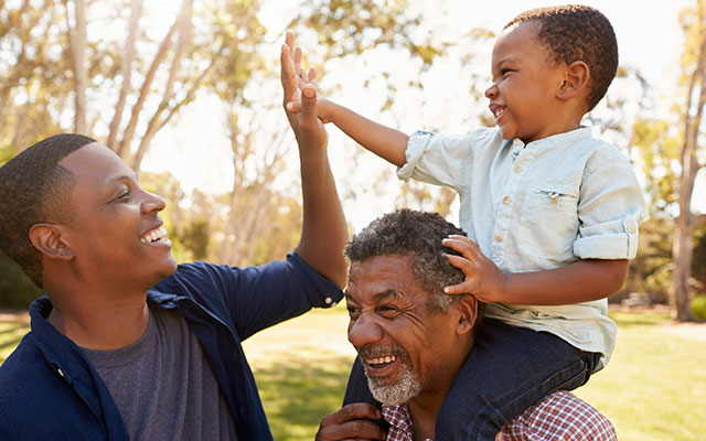 African-American father, grandfather and son playing in park